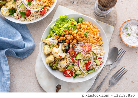 Vegan lunch bowl with roasted vegetables, fresh lettuce, cooked lentils, couscous salad and roasted chickpeas Vegan lunch bowl with roasted vegetables, fresh lettuce, cooked lentils, couscous salad and roasted chickpeas 122153950