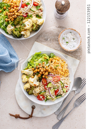 Vegan lunch bowl with roasted vegetables, fresh lettuce, cooked lentils, couscous salad and roasted chickpeas Vegan lunch bowl with roasted vegetables, fresh lettuce, cooked lentils, couscous salad and roasted chickpeas 122153951