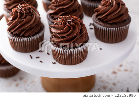 Chocolate cupcakes with chocolate ganache frosting and chocolate sprinkles 122153990