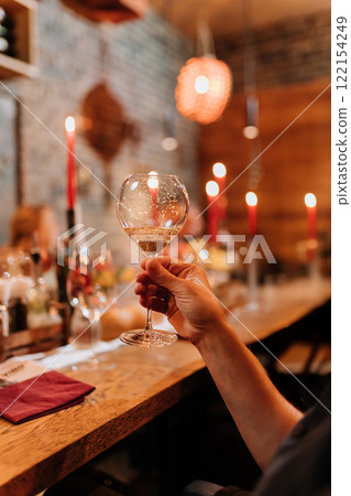 Raising a glass of sparkling wine in a warm, candlelit dinner setting for a festive celebration 122154249