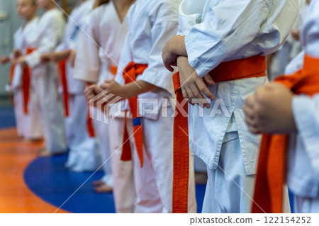 A close-up of a row of young athletes in white karate kimonos with clenched fists. A close-up of a row of young athletes in white karate kimonos with clenched fists. 122154252