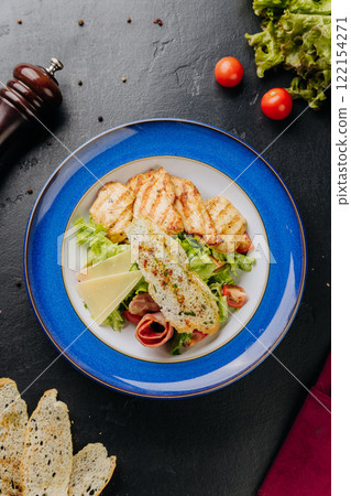 Grilled chicken salad with cheese slices, bacon, lettuce, and crispy bread for a hearty, fresh meal Grilled chicken salad with cheese slices, bacon, lettuce, and crispy bread for a hearty, fresh meal 122154271