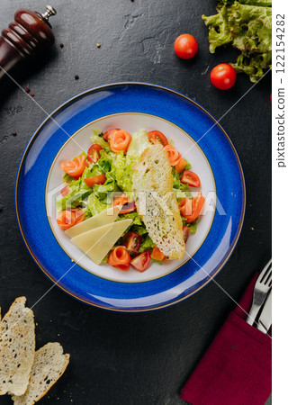 Fresh salmon salad with cherry tomatoes, lettuce, cheese slices, and crispy bread for healthy lunch 122154282
