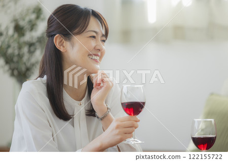 Woman holding a glass of alcohol in the living room 122155722