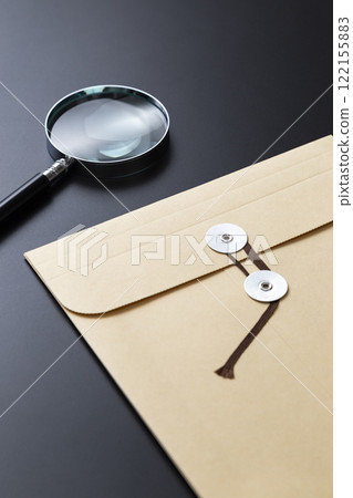Magnifying glass and envelope with string on black background 122155883