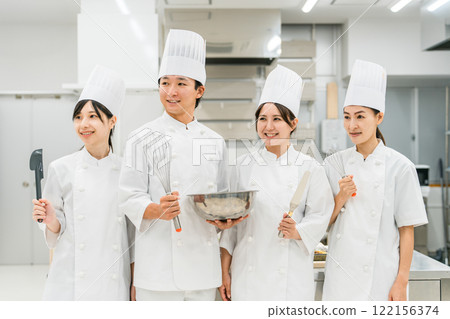 Chefs and cooks in chef coats standing in the kitchen Chefs and cooks in chef coats standing in the kitchen 122156374