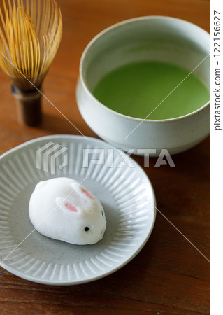 Cup of fresh matcha tea, green tea and Bunny Rabbit shape daifuku Japanese confectionery on wooden table. Cup of fresh matcha tea, green tea and Bunny Rabbit shape daifuku Japanese confectionery on wooden table. 122156627