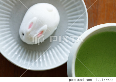 Cup of fresh matcha tea, green tea and Bunny Rabbit shape daifuku Japanese confectionery on wooden table. Cup of fresh matcha tea, green tea and Bunny Rabbit shape daifuku Japanese confectionery on wooden table. 122156628