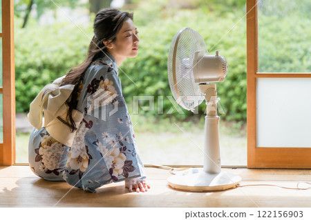 一位穿著浴衣的年輕女子在一座古老民宅的門廊上用扇子納涼。 122156903