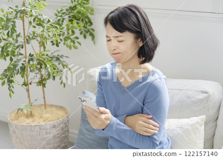 一位中年婦女拿著智慧型手機陷入困境，客廳 122157140