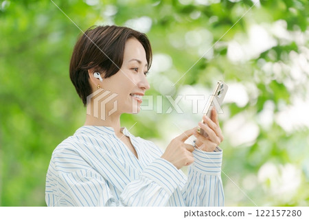 一個女人在新鮮的綠色中聽音樂 一個女人在新鮮的綠色中聽音樂 122157280