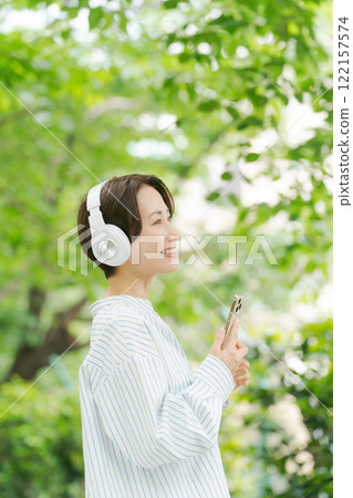 A woman in her 30s listening to music amidst the fresh greenery 122157574