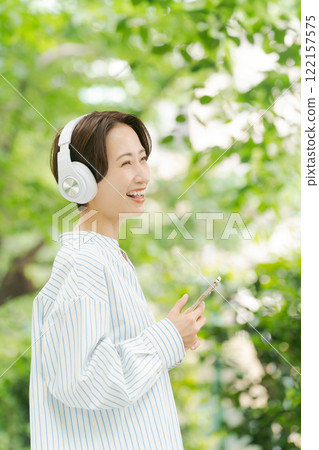 一位 30 多歲的女性在新綠中聽音樂 一位 30 多歲的女性在新綠中聽音樂 122157575