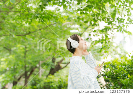 一位 30 多歲的女性在新綠中聽音樂 122157576