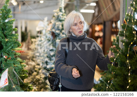 Mature woman choosing a Christmas tree Mature woman choosing a Christmas tree 122158166