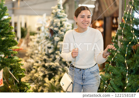 Woman choosing a Christmas tree Woman choosing a Christmas tree 122158187