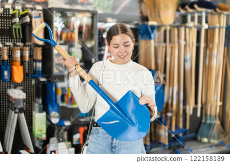 Woman choosing a shovel in a garden store Woman choosing a shovel in a garden store 122158189