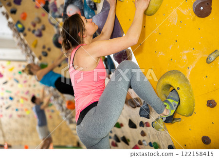 Female mountaineer climbing artificial rock wall without belay indoors 122158415
