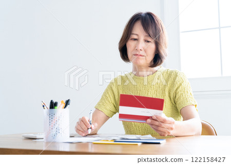 一名中年婦女一邊看存摺，一邊準備報稅 122158427