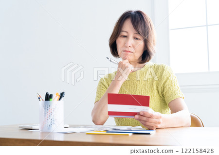 一名中年婦女一邊看存摺，一邊準備報稅 122158428