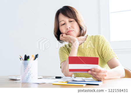 A middle-aged woman preparing her tax return while looking at her bankbook 122158431