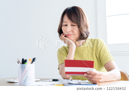 A middle-aged woman preparing her tax return while looking at her bankbook 122158432