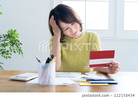 A middle-aged woman preparing her tax return while looking at her bankbook 122158434