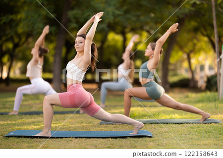 Group of girls practicing yoga at group session in sunny garden, performing Anjaneyasana, or Crescent Moon Pose Group of girls practicing yoga at group session in sunny garden, performing Anjaneyasana, or Crescent Moon Pose 122158643