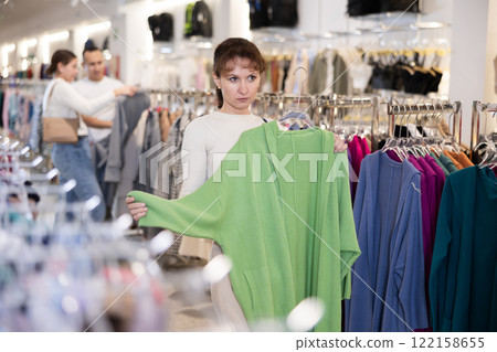 Adult woman chooses cardigan in store Adult woman chooses cardigan in store 122158655
