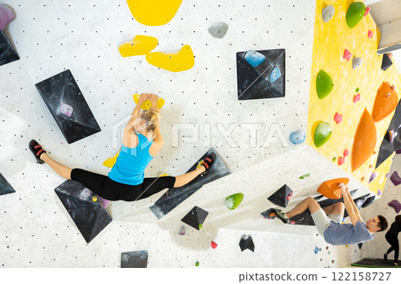 Woman and man alpinists practicing in pair indoor rock-climbing on climbing wall 122158727
