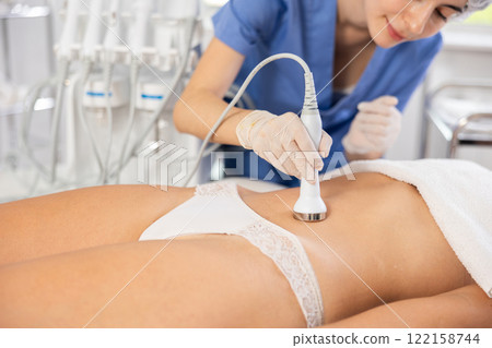 Female patient undergoing ultrasonic cavitation procedure on belly 122158744