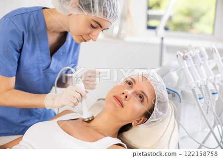 Female client undergoing anti-aging ultrasonic procedure on neck Female client undergoing anti-aging ultrasonic procedure on neck 122158758