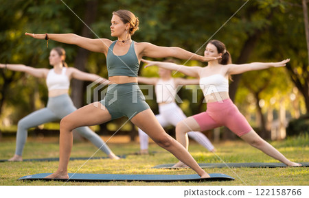 Yoga lesson visitors girls perform ardha virabhadrasana in park 122158766