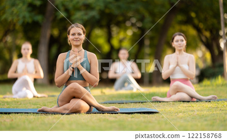 Yoga lesson visitors girls perform Gomukhasana in park 122158768
