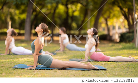 Yoga lesson visitors girls perform Urdhva Mukha Svanasana in park Yoga lesson visitors girls perform Urdhva Mukha Svanasana in park 122158812