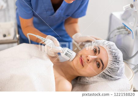 Female patient experiencing facial cryotherapy procedure in cosmetic clinic. Female patient experiencing facial cryotherapy procedure in cosmetic clinic. 122158820