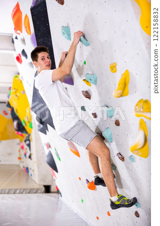 Young man exercising in climbing gym Young man exercising in climbing gym 122158832