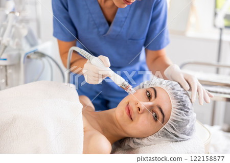 Woman undergoing cosmetic facial treatment using ion bubble attachment 122158877
