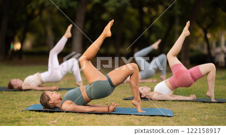 Athletic girls leading an active lifestyle, training in a summer park, performing dynamic asanas to improve body flexibility Athletic girls leading an active lifestyle, training in a summer park, performing dynamic asanas to improve body flexibility 122158917