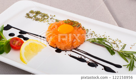 Tasty tartar with salmon, balsamic, yolk and lemon served on plate Tasty tartar with salmon, balsamic, yolk and lemon served on plate 122158956