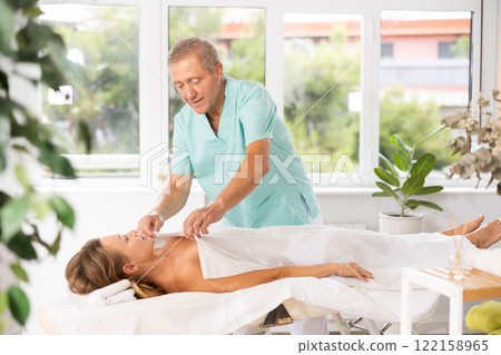 female patient under towel on massage table 122158965