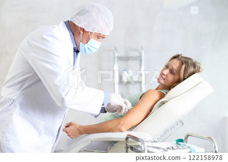 Man doctor makes an injection in arm of woman Man doctor makes an injection in arm of woman 122158978