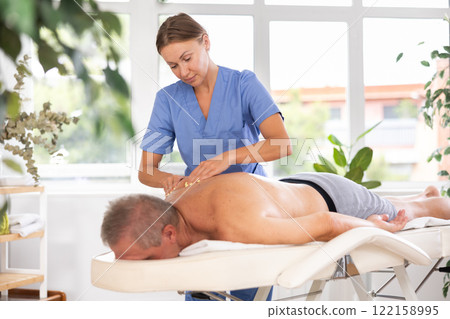 masseuse giving massage to male patient 122158995