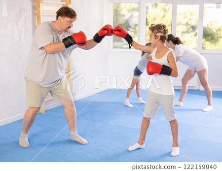 Boy and dad are boxing in gym, father helps child to work out force of blow. Boy and dad are boxing in gym, father helps child to work out force of blow. 122159040