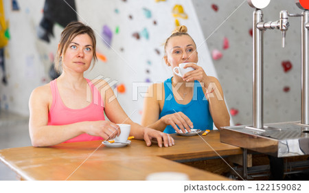 Two women drinking tea and chatting during break in bouldering gym Two women drinking tea and chatting during break in bouldering gym 122159082