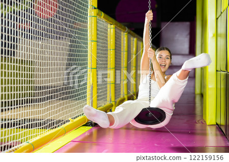 Happy girl goes down zip line at high speed in an amusement park. Storm of emotions and delight 122159156