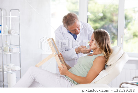 Elderly man doctor examining adult woman patient Elderly man doctor examining adult woman patient 122159198