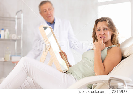 Upset adult woman looking at her face in mirror 122159221