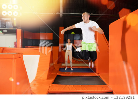 Male athlete training to jump on trampolines at trampoline center Male athlete training to jump on trampolines at trampoline center 122159281