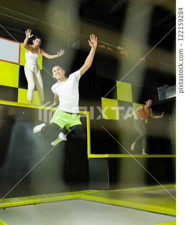 Emotional man jumping vertical and flying in trampoline sport center indoors Emotional man jumping vertical and flying in trampoline sport center indoors 122159284